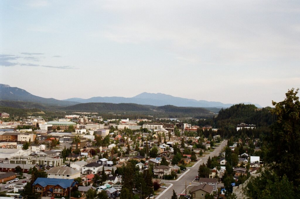 Residential and commercial buildings of downtown Whitehorse, with forests and mountains in the background.
