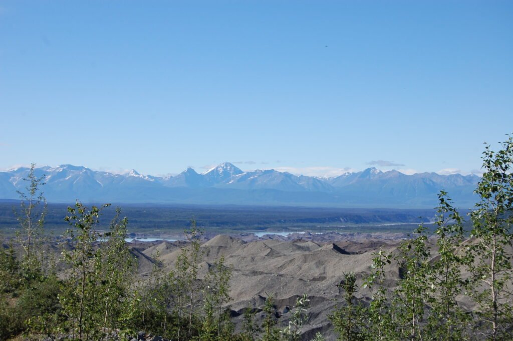 a debris-covered glacier with mountains in the far distance