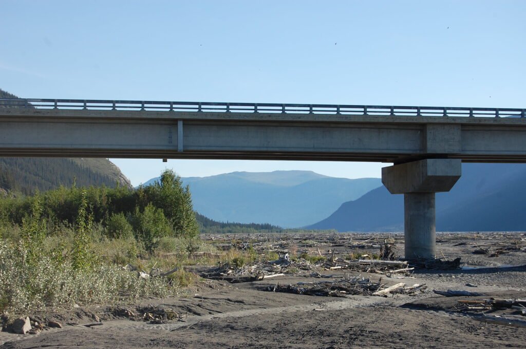 a multi-span bridge with mountains in the background framed between the piers