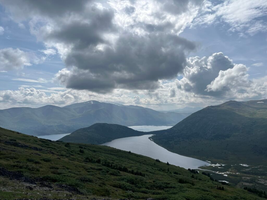 lakes and mountains, green with cloudy skies