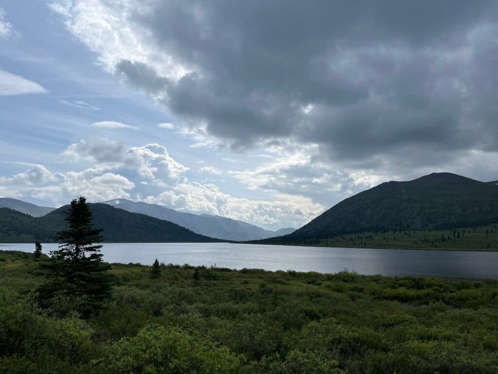 a lake in the foreground with layers of mountains in the background